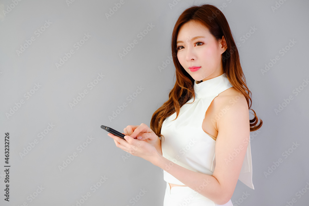 Portrait beautiful asian woman with mobile phone on gray background, emotions action Portrait beautiful asian woman with mobile phone on gray background, emotions action