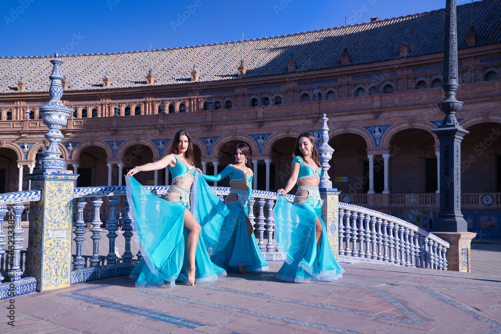 Three middle-aged Hispanic women, showing their turquoise and beaded costumes, for belly dancing. Belly dance concept.
