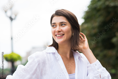 Attractive, happy and stylish brunette Caucasian girl posing on the street. Lifestyle and fashion concept.