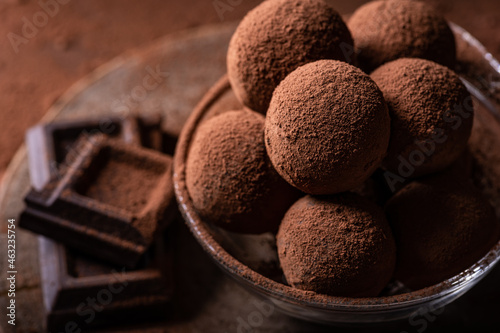 Tasty dark chocolate truffles with cocoa dusting on a brown background photo