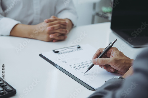 Executive sitting on the desk. Read Employee Resignation Letter and signs the resignation letter for the employee.changing and resigning from work concept for quit or change of job leaving the office