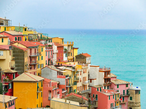 Beautiful colourful historic houses on the hills of Manarola, a popular tourist attraction destination, part of the famous Cinque Terre towns, Italy  UNESCO site. High angle view, sea in background © Kandl Studio