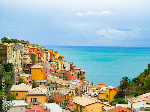 Beautiful colourful historic houses on the hills of Manarola, a popular tourist attraction destination, part of the famous Cinque Terre towns, Italy; UNESCO site. High angle view, sea in background