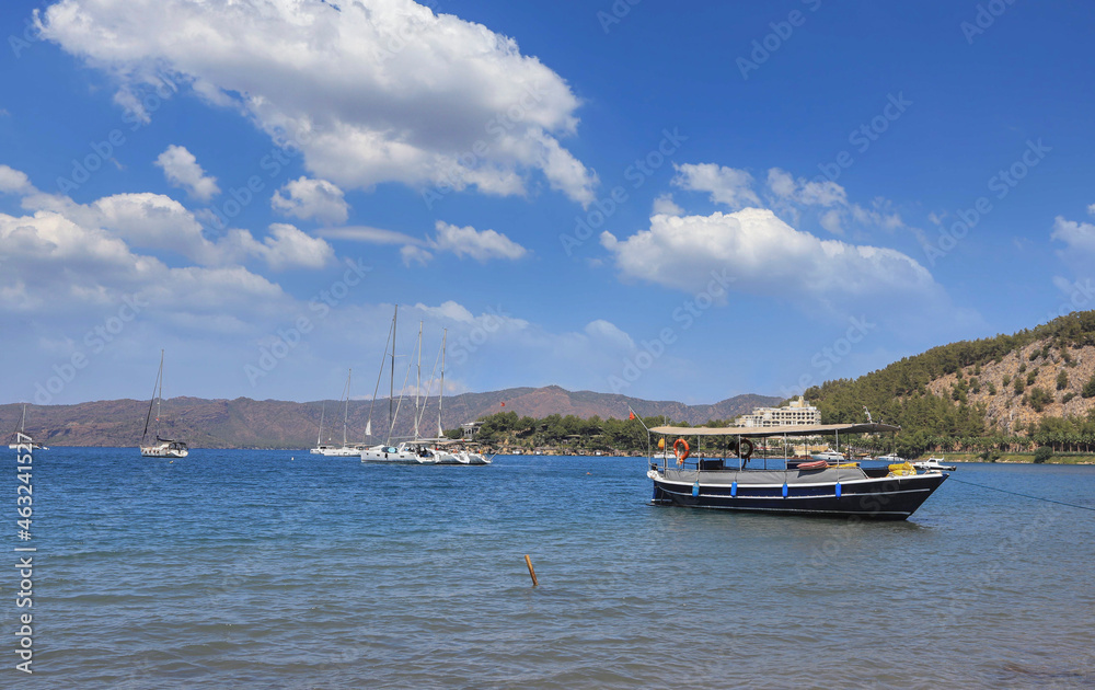 Turkey -Marmaris - Boats on the beach of Turgut village, a cloudy blue sky in the background.