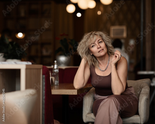 portrait of an adult pretty blonde woman in an elegant suit in a cafe