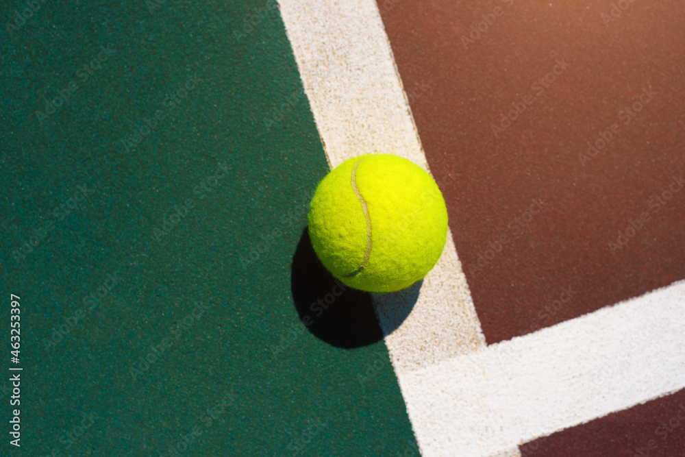 Yellow tennis ball lying on line of the red and green court. Flat lay view. Space for text