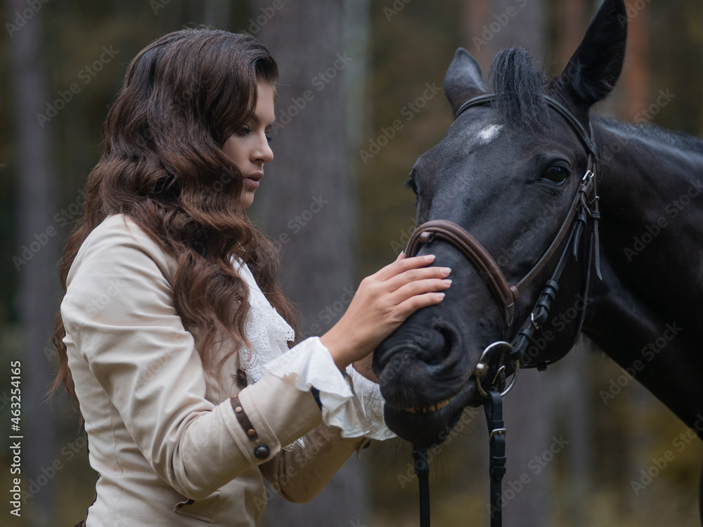 Obraz premium Portrait of a rider in a retro suit and her black horse.