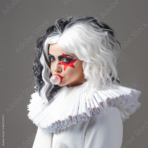 Fotografie woman in bright makeup and with black and white hairstyle blows a bubble of gum