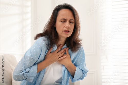 Mature woman suffering from breathing problem at home photo