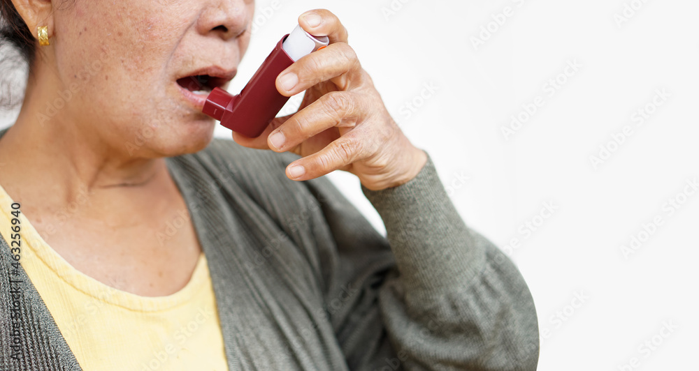 Female senior patient uses brown asthma inhaler for relief asthma