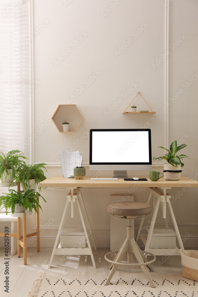 Comfortable workplace with modern computer and houseplants in room. Interior design Comfortable workplace with modern computer and houseplants in room. Interior design