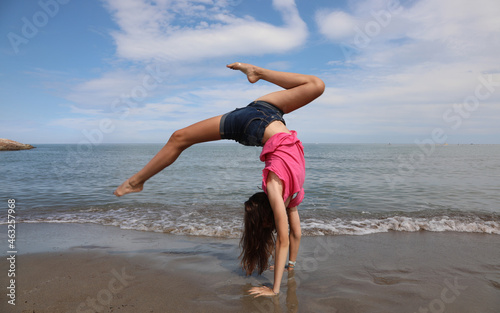 girl does a spin and reverse wheel During exercises by the sea photo