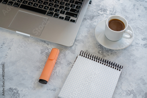 there is a laptop on the table, a mug of coffee and a notebook next to it