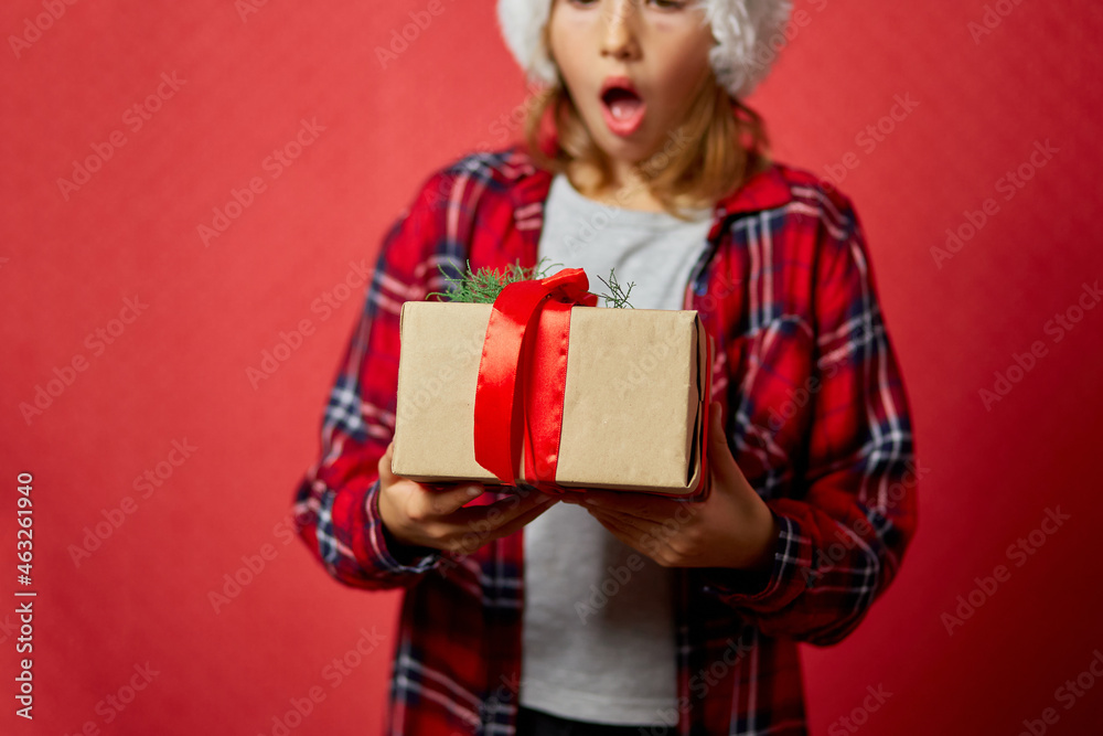 Surprised and Positive little girl in santa hat holding Christmas present