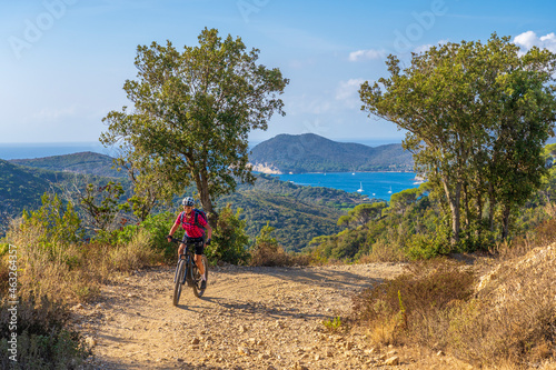 nice woman riding her electric mountain bike on the coastline above the mediterranean sea on the Island of Elba in the tuscan Archipelago, Tuscany, Italy © Uwe