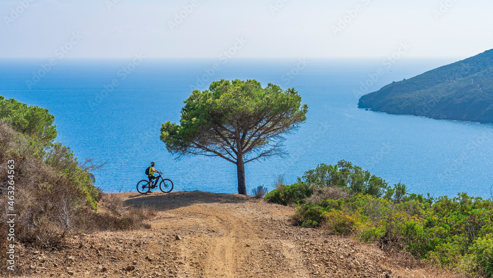nice woman riding her electric mountain bike at the coastline of mediterranean sea on the Island of Elba in the tuscan Archipelago Tuscany, Italy nice woman riding her electric mountain bike at the coastline of mediterranean sea on the Island of Elba in the tuscan Archipelago Tuscany, Italy