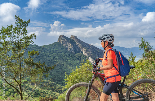 nice woman riding her electric mountain bike on the coastline above the mediterranean sea on the Island of Elba in the tuscan Archipelago, Tuscany, Italy