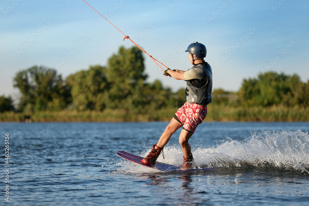 Fototapeta premium Teenage boy wakeboarding on river. Extreme water sport