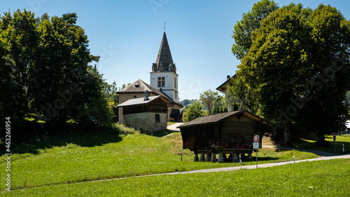 Picturesque alpine summer landscape view with small white church, wooden buildings,  trees and green pastures - Cergnat, Ormont-Dessous near Aigle in Swiss canton of Vaud, Switzerland