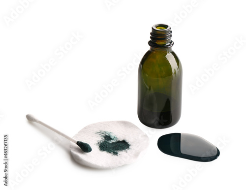 Glass bottle, cotton pad, bud and spilled brilliant green on white background photo