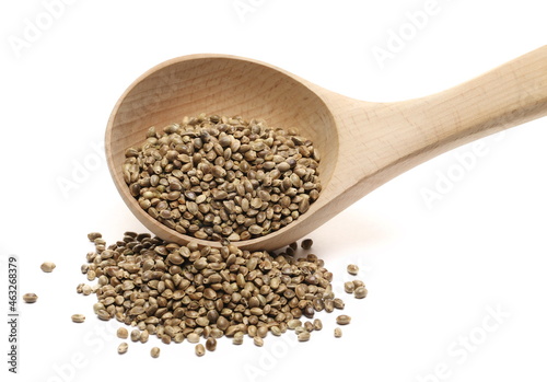 Hemp seeds pile with wooden spoon isolated on white  