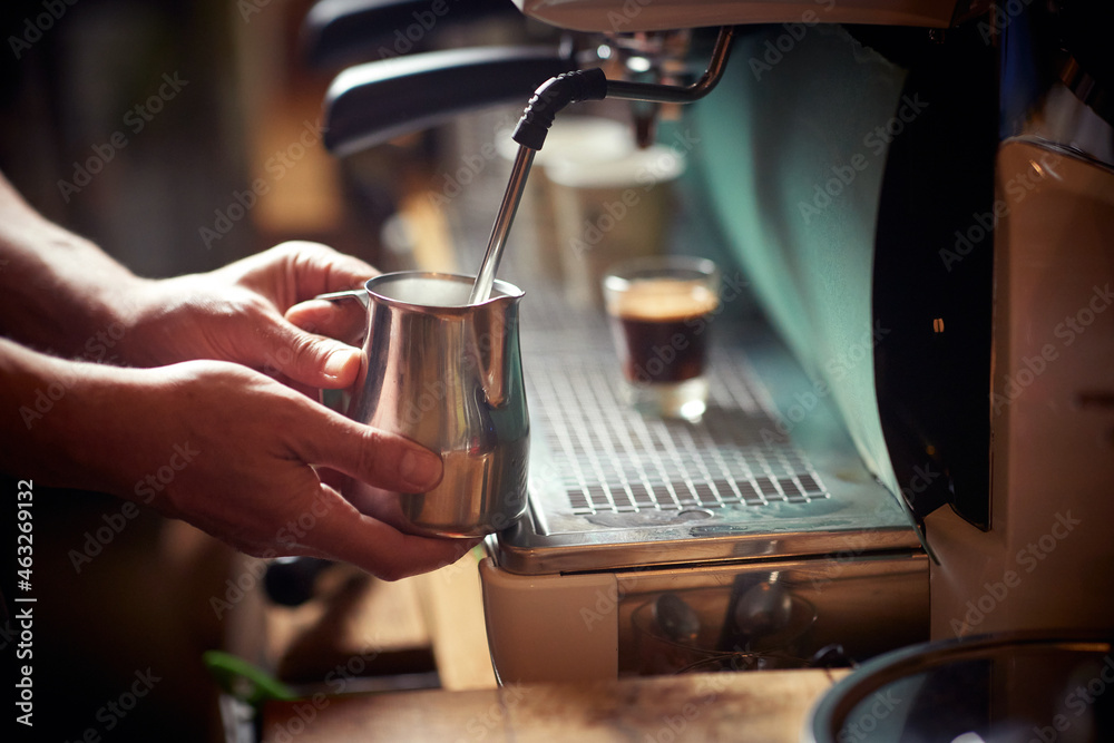 A milk in the container being boiled in the espresso apparatus by a barman. Coffee, beverage, bar