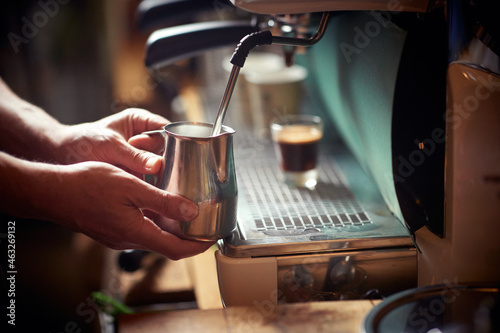 A milk in the container being boiled in the espresso apparatus by a barman. Coffee, beverage, bar