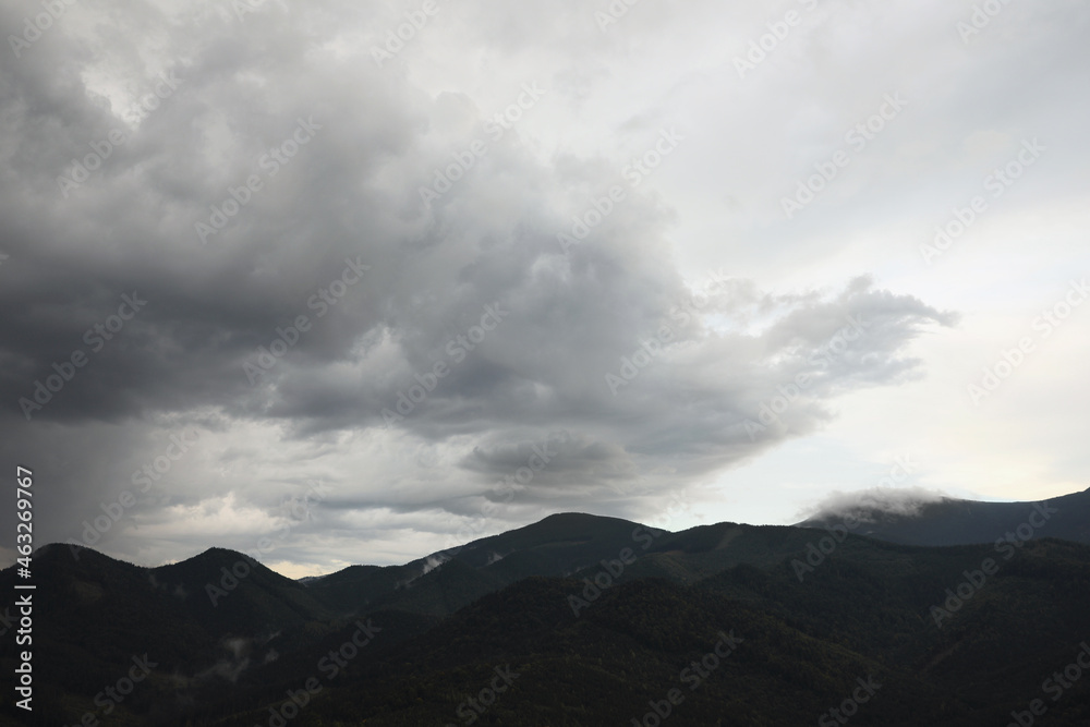 View of sky with grey thunder clouds over mountains