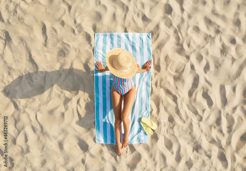 Photography Woman sunbathing on beach towel at sandy coast, aerial view