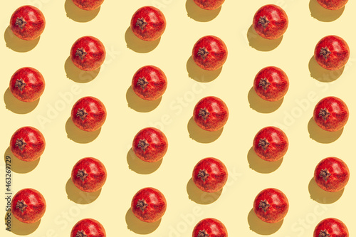Creative pattern made of fresh pomegranates on yellow sunlit background. Minimal style. Top view. Flat lay .