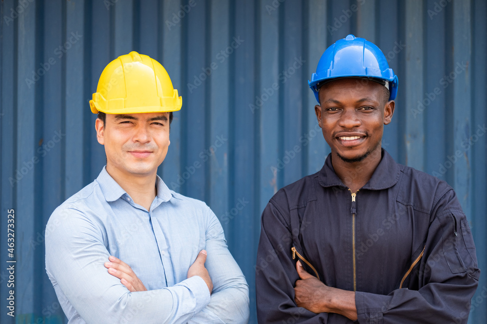 Caucasian supervisor and African men worker standing with arm crossed while inspect the condition of all containers shipment, People and worker in freight deliver, import and export teamwork Caucasian supervisor and African men worker standing with arm crossed while inspect the condition of all containers shipment, People and worker in freight deliver, import and export teamwork