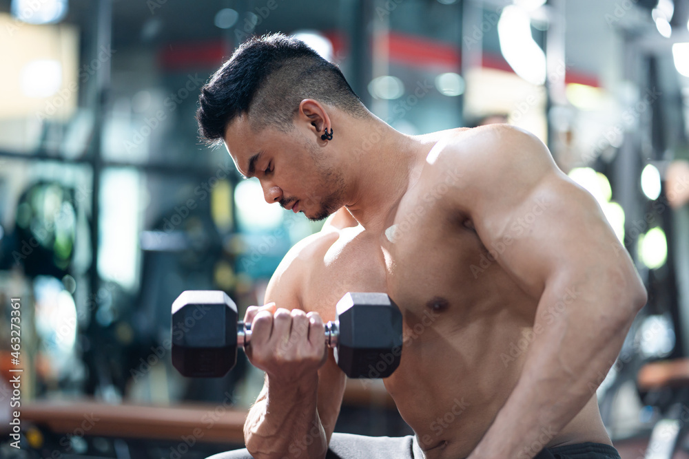 Handsome shirtless adult Asian men sweating while lift up the dumbbell