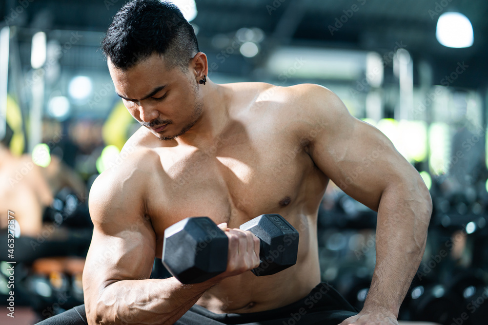 Handsome shirtless adult Asian men sweating while lift up the dumbbell