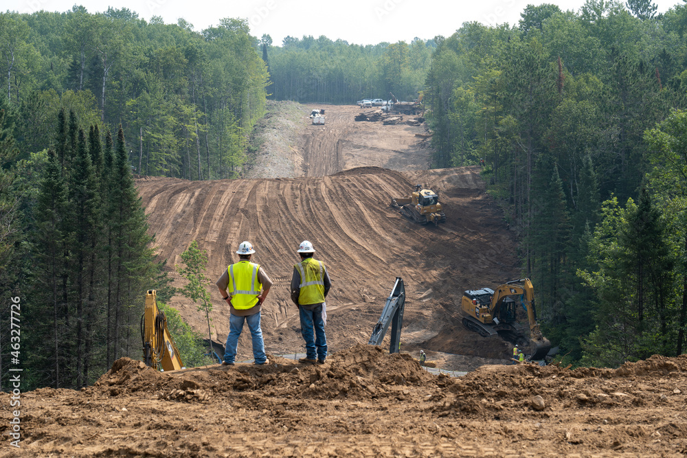 CASS CO, MN - 6 AUG 2021: Enbridge Line 3 Oil Pipeline Construction Site in Minnesota forest with excavators and bulldozers covering the installed pipe. Foreground is intentionally out of focus.
