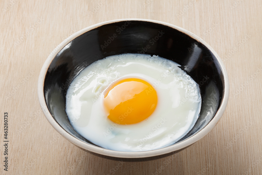 fried egg in a ceramic bowl on wooden background fried egg in a ceramic bowl on wooden background