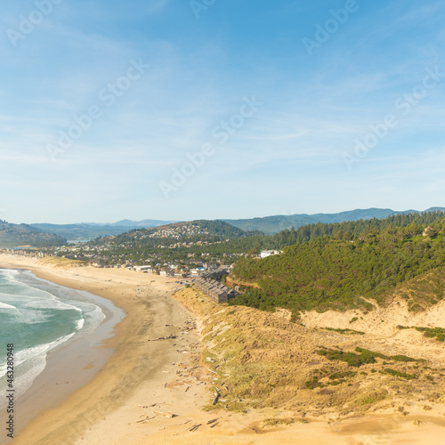 Sandy hilly, overgrown with green grass coast of the ocean. A mountain range can be seen in the distance. Blue sky. Calm scenes. Beautiful landscape. There are no people in the photo.