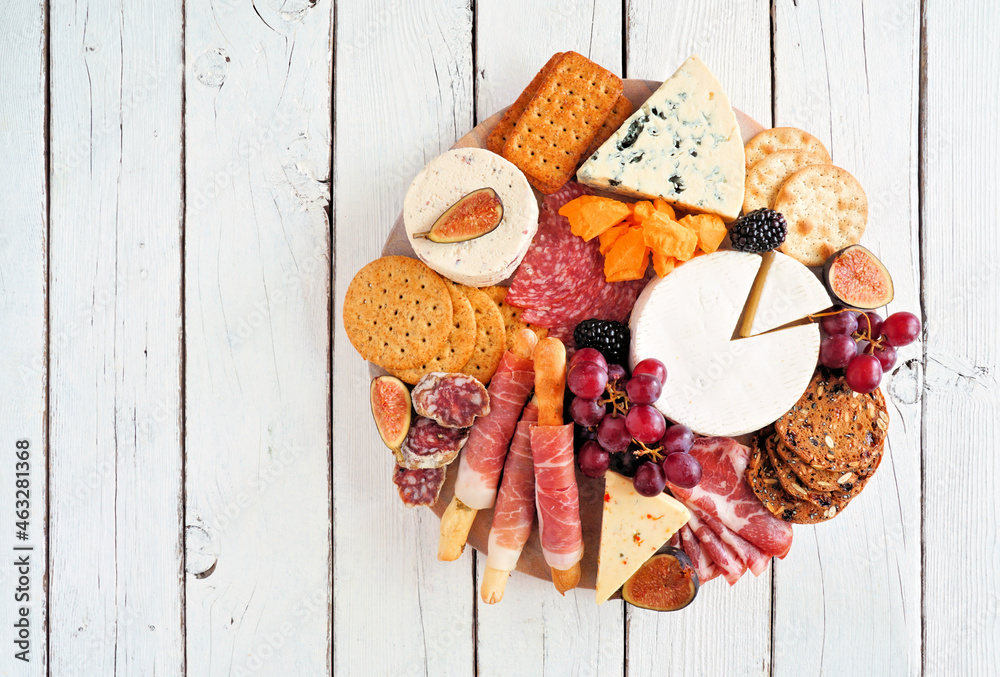 Charcuterie platter with different meats, cheeses and appetizers. Top view on a white wood background. - obrazy, fototapety, plakaty 
