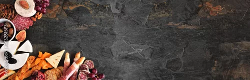 Panel kuchenny z motywem Selection of cheese and meat appetizers. Above view corner border on a dark slate banner background with copy space.