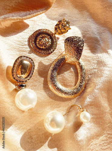 Background of accessories. A set of beautiful precious jewelry made of gold and pearls on a silk scarf. Fashion photos