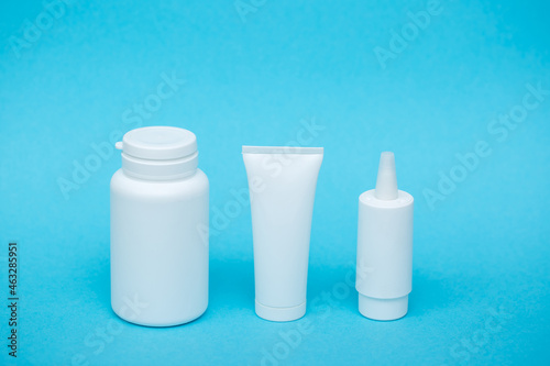 White different medical or cosmetic jars on a blue background as a concept of cosmetology of medecine and treatment