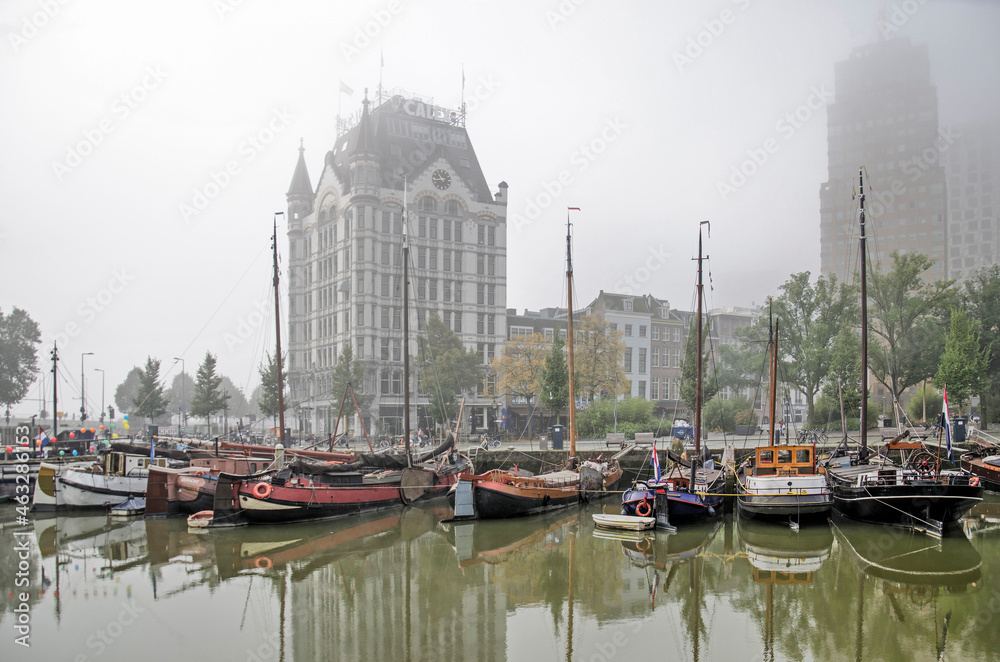 Rotterdam, The Netherlands, October 8, 2021: historic vessel and the White House reflect in the Old Harbour on a misty and windless day