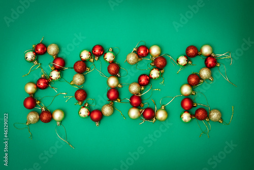 Christmas balls of red and gold on a green background are laid out in the form of the number 2022. 