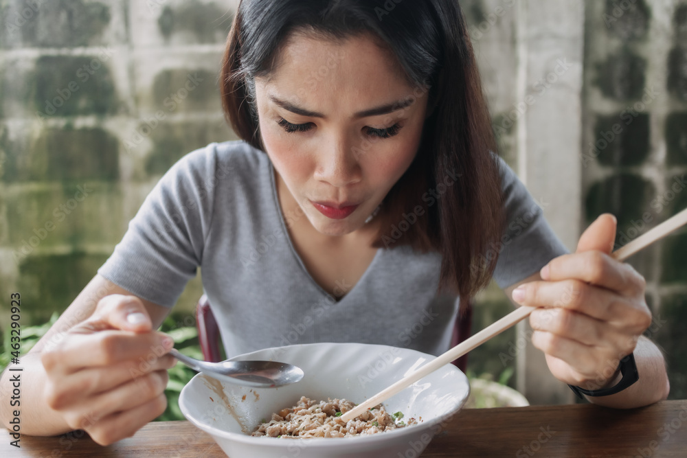 Asian woman eat spicy noodles with chopsticks in local street. Asian woman eat spicy noodles with chopsticks in local street.