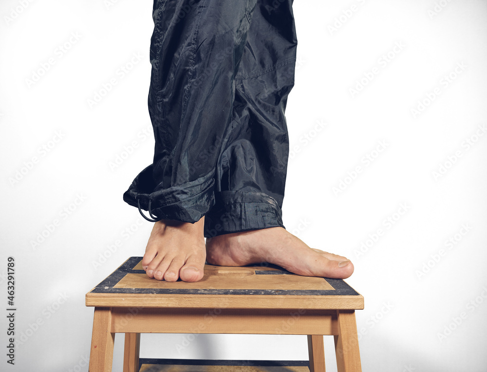Fototapeta premium Male feet standing barefoot on chair making pose