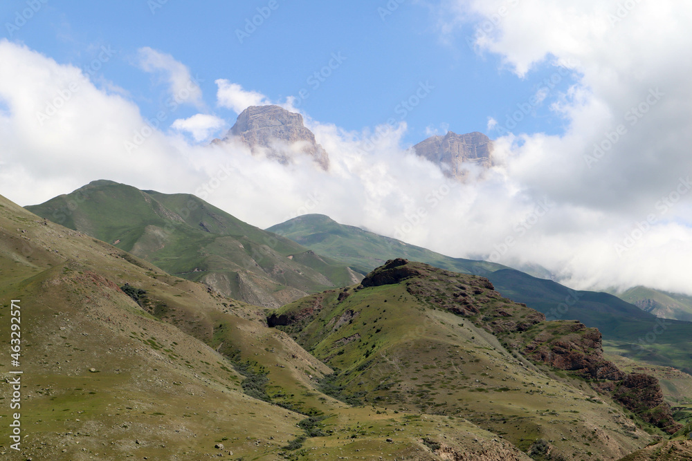 Rocky peaks in the clouds above green Caucasus mountains