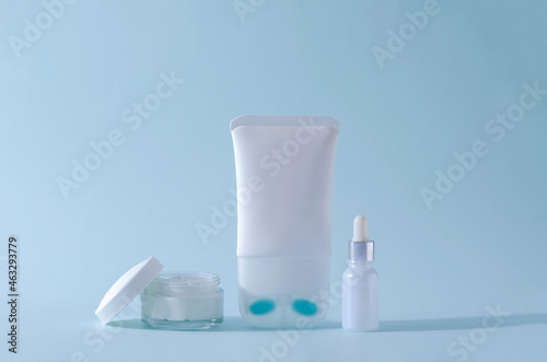 Cream for skin care of the neck and decollete in a white tube, serum in a glass white bottle, cream in a glass jar. Cosmetics for skin care. photo