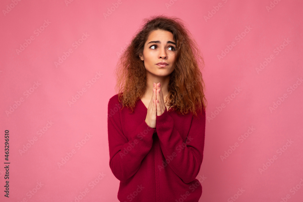 Photo of young emotional beautiful brunette curly woman with sincere emotions wearing trendy pink pullover isolated over pink background with free space and keeping hands in praying gesture and Photo of young emotional beautiful brunette curly woman with sincere emotions wearing trendy pink pullover isolated over pink background with free space and keeping hands in praying gesture and