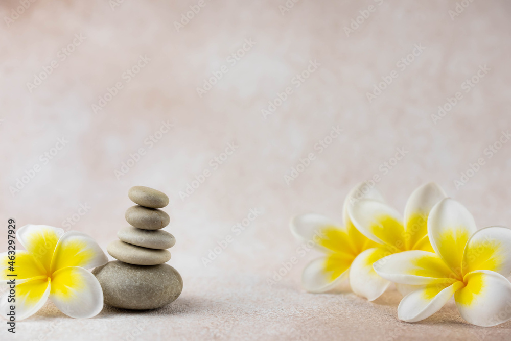 Pyramids of gray and white zen pebble meditation stones on beige background with plumeria tropical flower. Concept of harmony, balance and meditation, spa, massage, relax Pyramids of gray and white zen pebble meditation stones on beige background with plumeria tropical flower. Concept of harmony, balance and meditation, spa, massage, relax