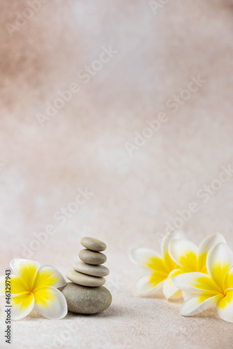 Canvas Print Pyramids of gray and white zen pebble meditation stones on beige background with plumeria tropical flower