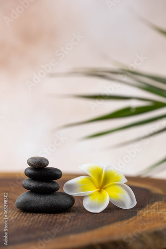 Pyramids of gray and white zen pebble meditation stones on beige background with plumeria tropical flower. Concept of harmony, balance and meditation, spa, massage, relax